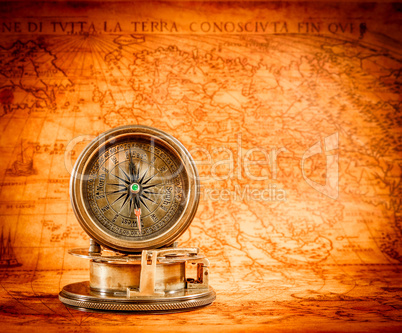 Vintage compass lies on an ancient world map.