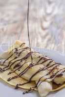 chocolate sauce pouring on crepe