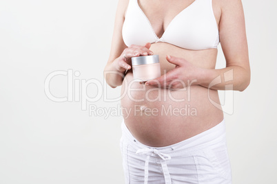 Pregnant woman holding creme in her hands
