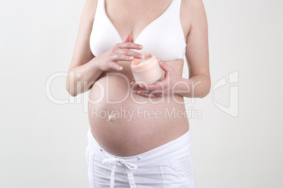 Pregnant woman putting creme on her belly