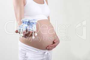 Pregnant woman holding blue baby shoes in her hands