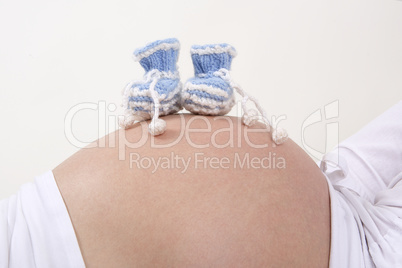 Pregnant woman with blue baby shoes on her belly