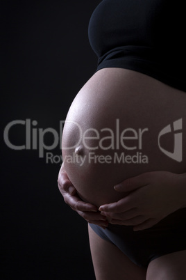 Pregnant woman in front of black background