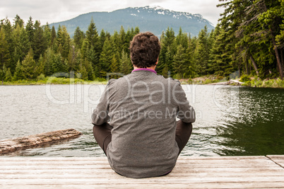Junger Mann meditiert am See