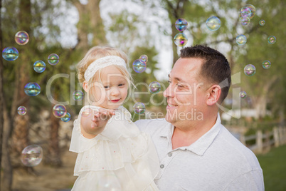 Father Holding Baby Girl Enjoying Bubbles Outside at Park