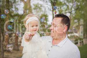 Father Holding Baby Girl Enjoying Bubbles Outside at Park