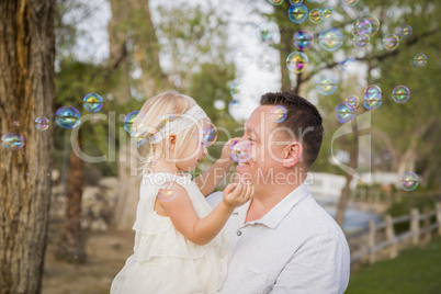 Father Holding Baby Girl Enjoying Bubbles Outside at Park