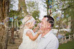 Father Holding Baby Girl Enjoying Bubbles Outside at Park