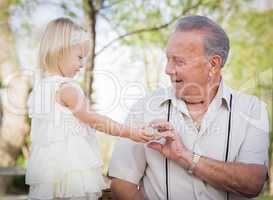 Cute Baby Girl Handing Easter Egg to Grandfather Outside