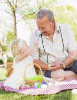 Grandfather and Granddaughter Coloring Easter Eggs on Blanket At