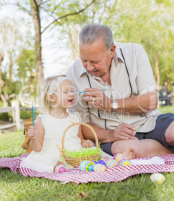 Grandfather and Granddaughter Coloring Easter Eggs on Blanket At