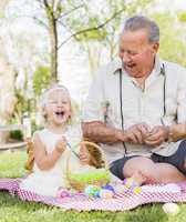 Grandfather and Granddaughter Coloring Easter Eggs on Blanket At