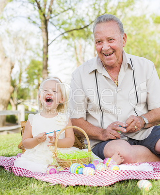 Grandfather and Granddaughter Coloring Easter Eggs on Blanket At