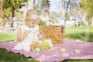 Cute Baby Girl Coloring Easter Eggs on Picnic Blanket