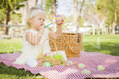 Cute Baby Girl Coloring Easter Eggs on Picnic Blanket