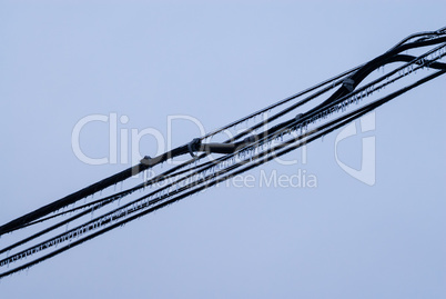 Black cables covered in ice on gray