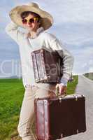 Woman with straw hat and sunglasses wearing holiday suitcase