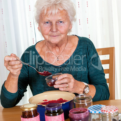 Senior woman filling homemade jam in the glass