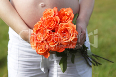 Pregnant woman outdoor with orange tulips in her hands