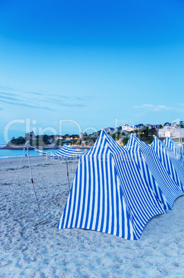 White and blue tents on the beach at sunset