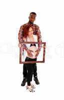 Pregnant couple holding picture frame.