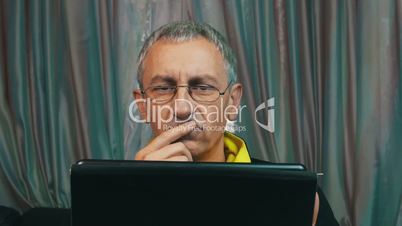Portrait Dissatisfied Man in Glasses Reading a Tablet Computer, closeup