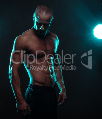 Shirtless Athletic Man Looking Down with Spotlight