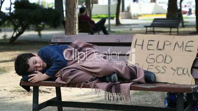 Homeless, tired child resting on a park bench