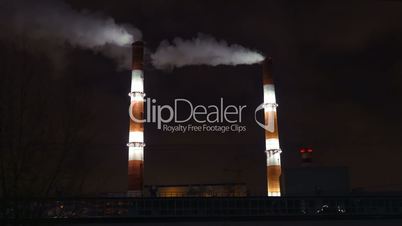 Smoking factory pipes in the city at night
