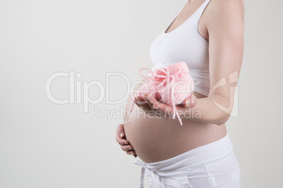 Pregnant woman holding pink baby shoes in her hands