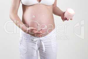 Pregnant woman putting smiley with creme on her belly