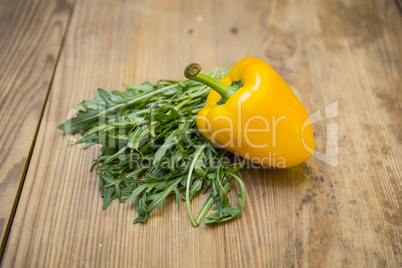 Gelbe Paprika und Rucola auf Holzplatte