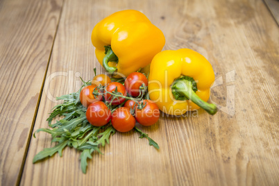 Gelbe Paprika, Tomaten und Rucola auf Holzplatte