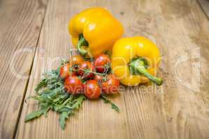 Gelbe Paprika, Tomaten und Rucola auf Holzplatte