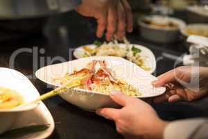 Hand mit Teller und Pasta mit Schinken