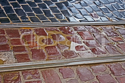 Fragment of wet cobbled road with tram tracks