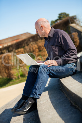 Man sitting on a bench using a laptop