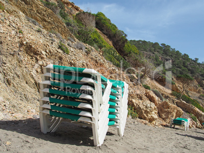 gestapelte Strandliegen an der Cala Boix, Ibiza