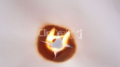 Flamme brennt kreisförmig ein Loch in Papier
