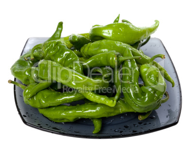 Wet green peppers on glass plate