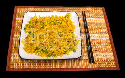 Rice with vegetables and chopsticks on bamboo mat