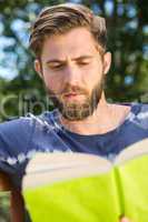 Young man reading on park bench