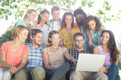 Friends looking at laptop in the park