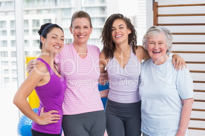 Happy women standing arms around in gym