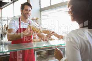 Smiling baker doing loaf transaction with customer