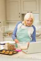 Happy blonde preparing dough following online recipe