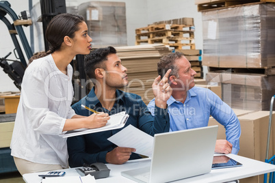 Warehouse manager pointing something to his colleagues