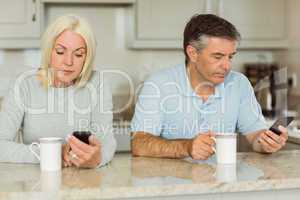 Mature couple having coffee and using phones
