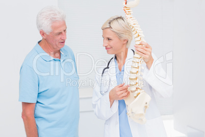 Doctor and senior patient discussing over anatomical spine