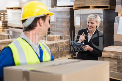 Warehouse worker holding box with manager behind him